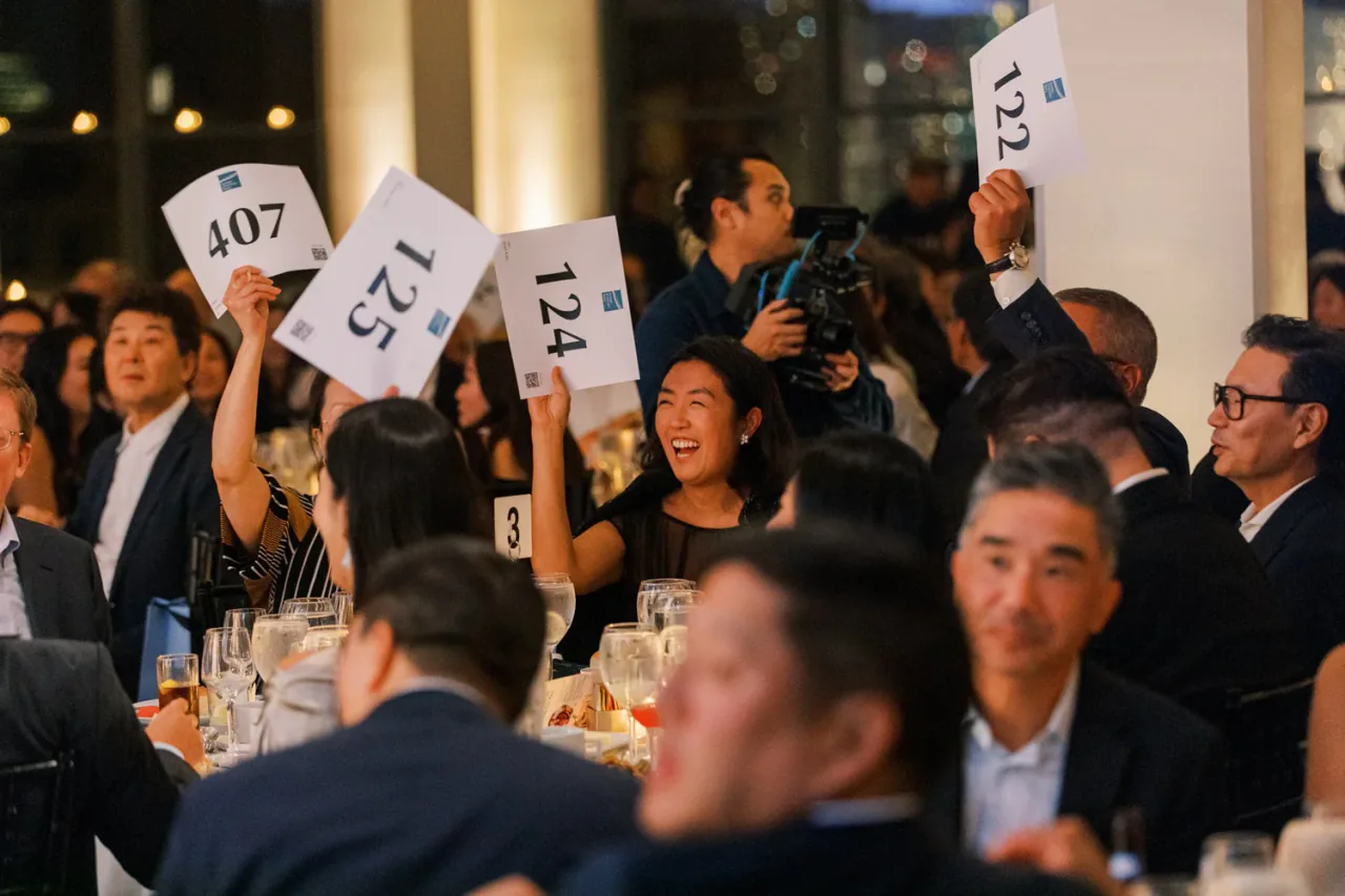 Guests laughing and raising bid paddles at a charity auction