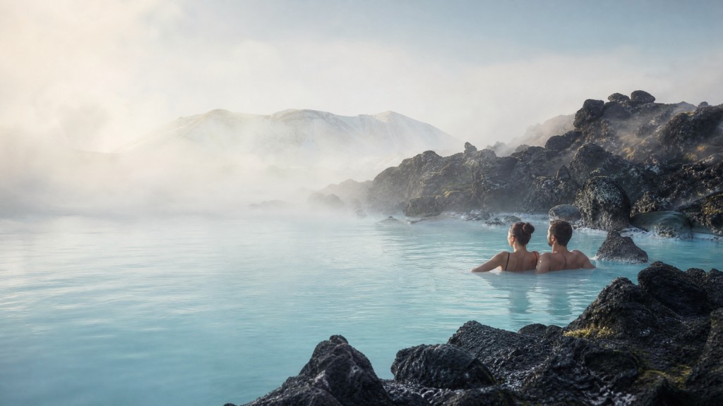 Couple soaking in a misty geothermal lagoon with volcanic rocks